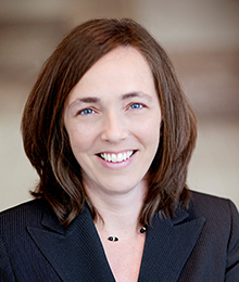Kristin Norse headshot, Caucasian businesswoman with brown hair wearing a dark navy suit
