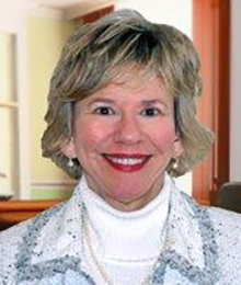 Susan Churuti headshot, Caucasian woman, smiling and wearing a white turtleneck with a light colored jacket