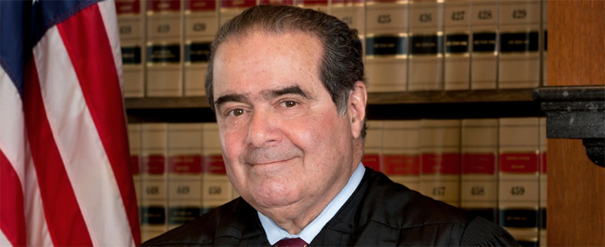 Justice Antonin Gregory Scalia headshot, Caucasian male wearing black suit is pictured in front of a wall of legal books