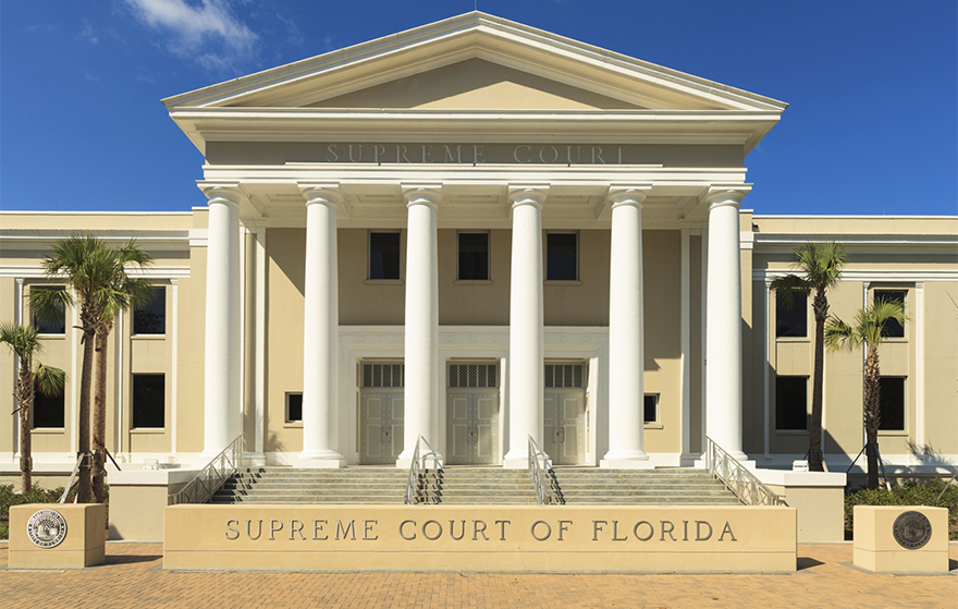 Supreme Court of Florida is pictured on a sunny day with blue skies, building is historic with large pillars and a grand set of steps out front
