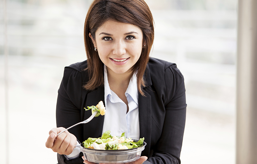 Young businesswoman eats a healthy salad for lunch