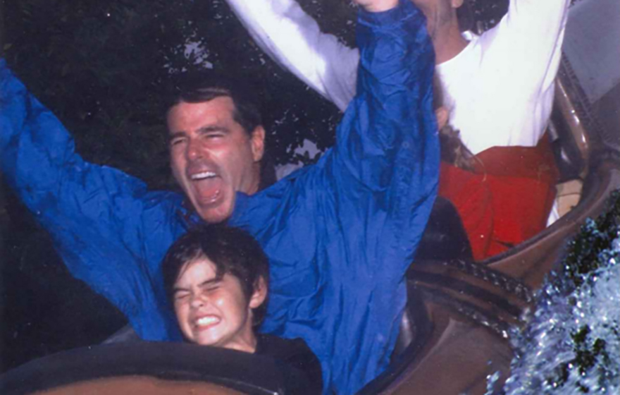Bill Schifino is pictured with a young boy on a roller coaster ride