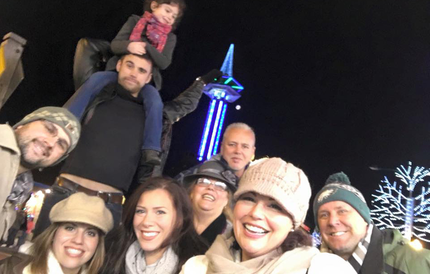 Michelle Suarez is pictured with a group of people outdoors at night in a chilly downtown setting