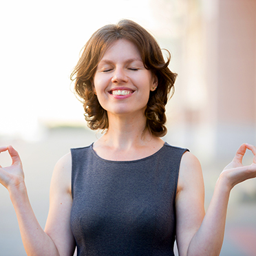Relaxed woman stands outside, eyes closed, enjoying life