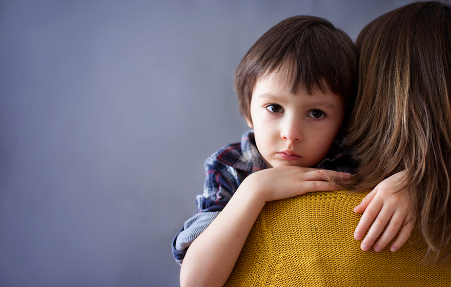 Lonely looking young boy being carried by mother looks over her shoulder