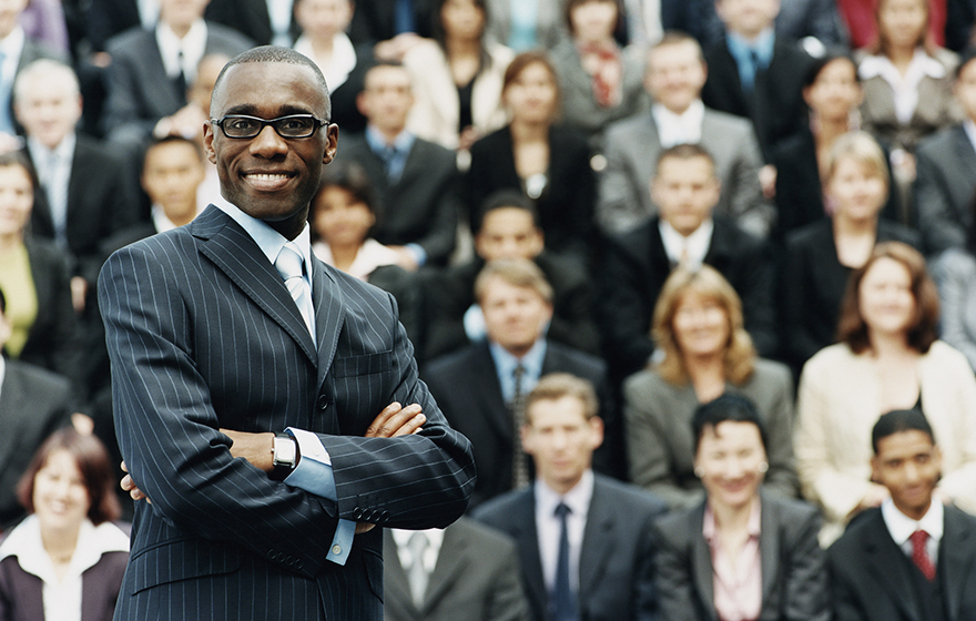 African American Male Lawyer in suit standing in front of large group of other lawyers in suits
