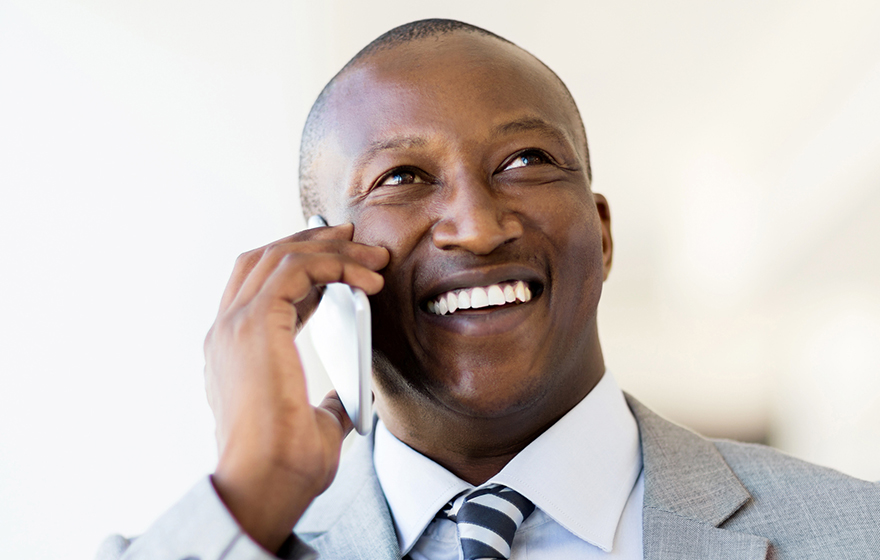 cheerful African American businessman talking on smart phone in office