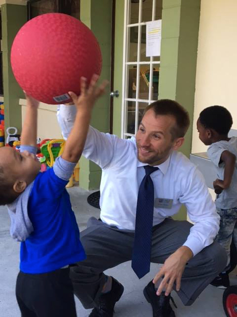 John Miller with a young child holding a ball