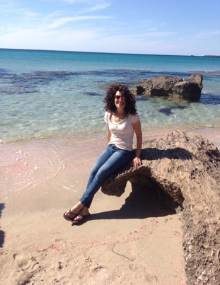 Judge Eleni Derke, caucasian woman in jeans in t-shirt sitting on a rock next to the ocean