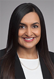 Anisha Patel headshot, Indian Woman, Black Blazer, White Blouse, Pearl Necklace, Smiling, Long Black Hair, Brown Eyes