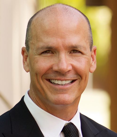 Jason Gunter headshot of a middle aged smiling Caucasian man wearing a black suit and a black dotted tie