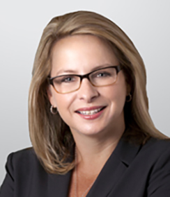 Michelle Suarez headshot of a young Caucasian woman wearing glasses. She has brown hair and is smiling.