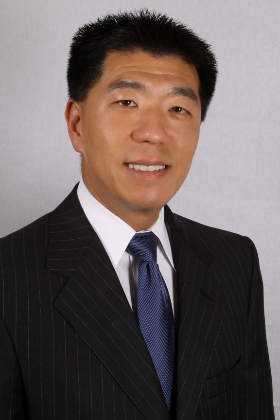 Jay Kim headshot of a smiling Asian man in a black suit with a white shirt wearing a dark blue tie