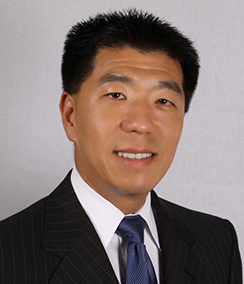 Jay Kim headshot of a smiling Asian man in a black suit with a white shirt wearing a dark blue tie