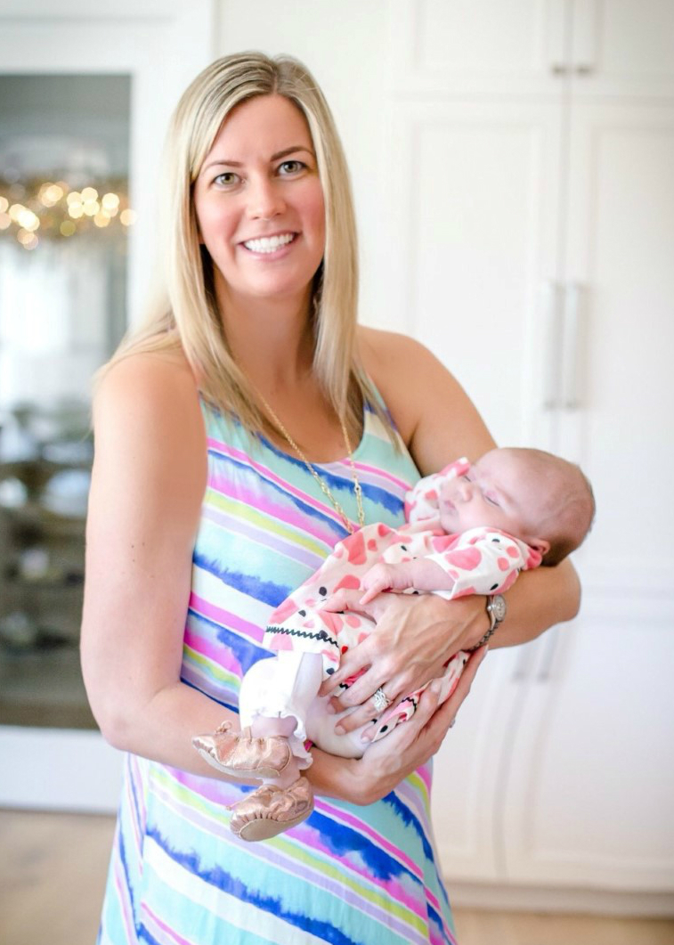 Kevyn Noonan Hayes a young smiling Caucasian mother with blonde hair with her newborn baby girl dressed in pink polka dots.