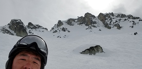 Jay Kim an Asian man in a helmet standing on the side of a snow covered mountain