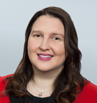 Mandi Clay headshot of a Caucasian woman in a black and red blouse with medium length curled brown hair.