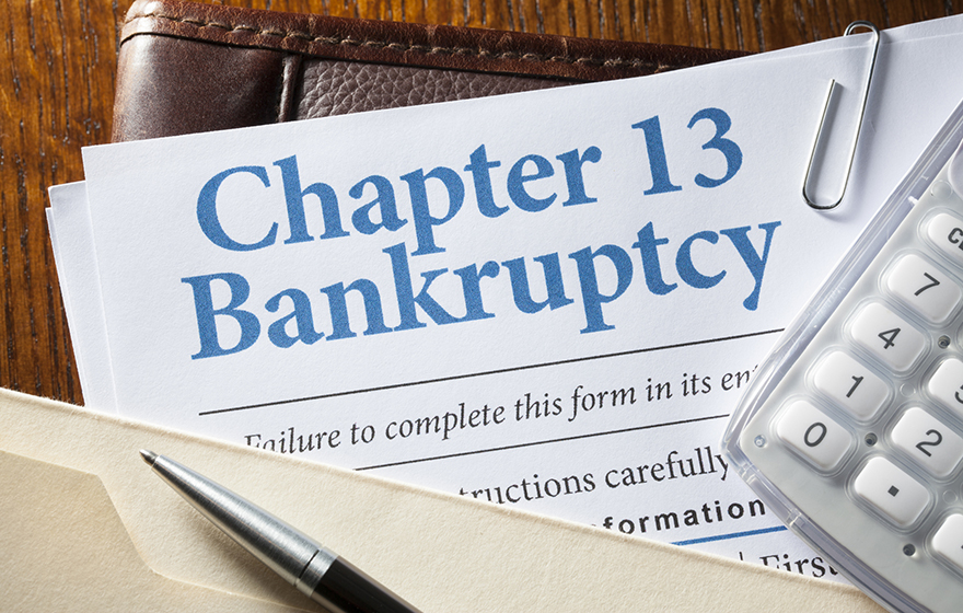 Documents for filing Chapter 13 bankruptcy, a calculator and pen are partially visible in the photograph