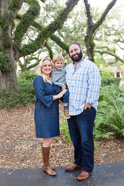 Casseland Cassel a Caucasian woman with blonde hair wearing a blue with her Caucasian husband who has a black beard and black hair and their young blonde son