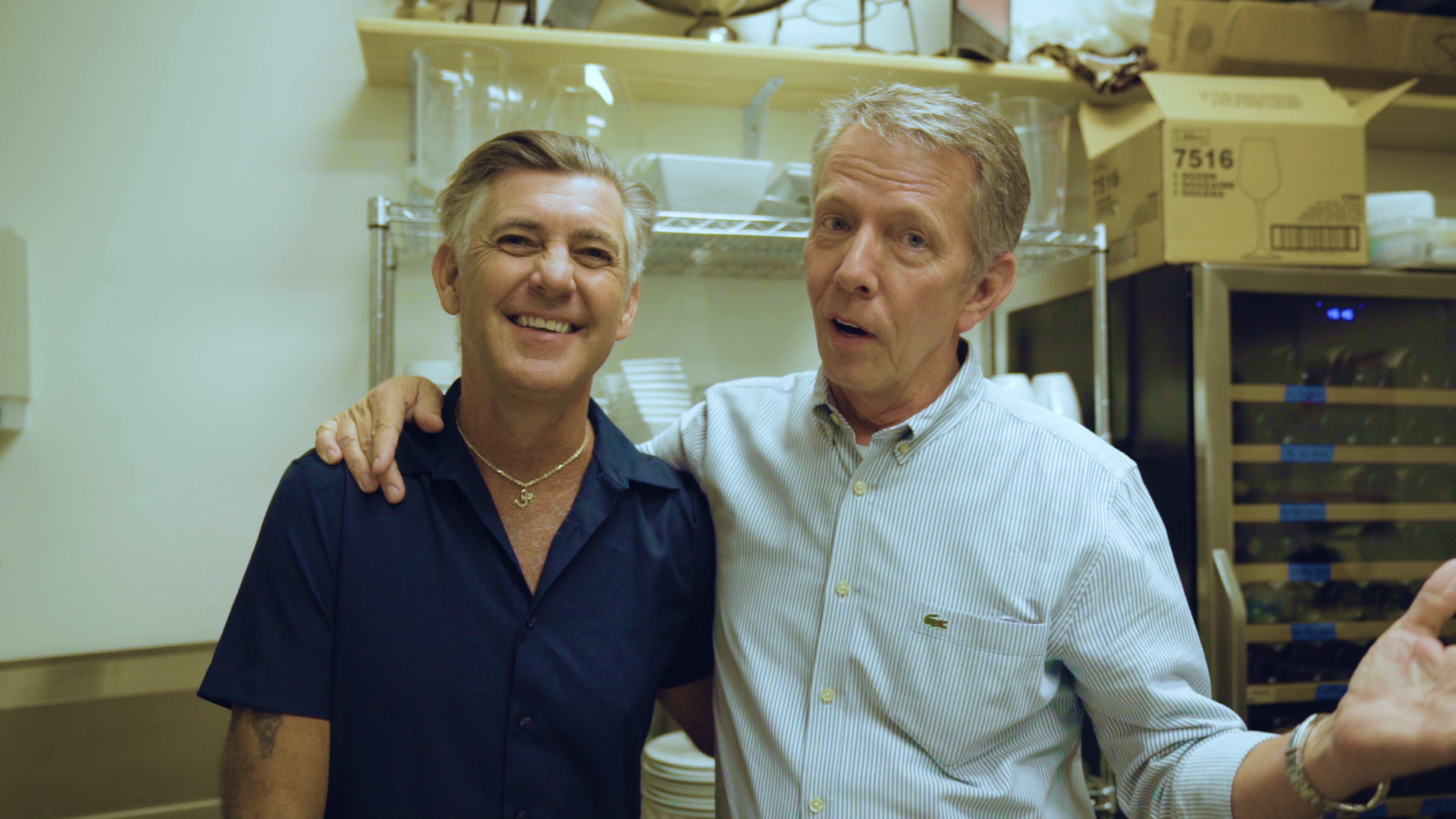 Wayne LaRue Smith a Caucasian man standing in kitchen with another Caucasian man wearing a gold necklace