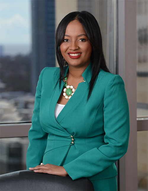 Alison Smith headshot African American woman in a teal blazer and white shirt in front of office window, she is smiling and wearing lipstick, and has long black hair.