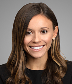 Melina Garcia headshot, Young Latina woman with long brown hair and brown eyes who is smiling. She is wearing pearl earrings and a black top.