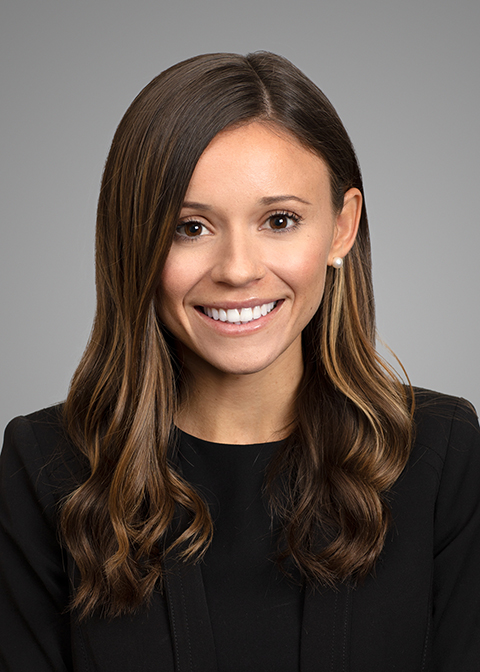 Melina Garcia headshot, Young Latina woman with long brown hair and brown eyes who is smiling. She is wearing pearl earrings and a black top.