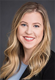 Rachel Butler headshot, Caucasian Woman in a Black Blazer with blue shirt, long blonde hair, smiling with red lipstick