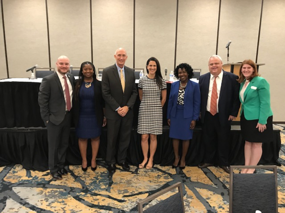 Government Lawyers Committee Update 3 seven people standing and smiling, four women, two african American women, two caucasian women, three caucasian men, business suits, blazers, skirts, dress
