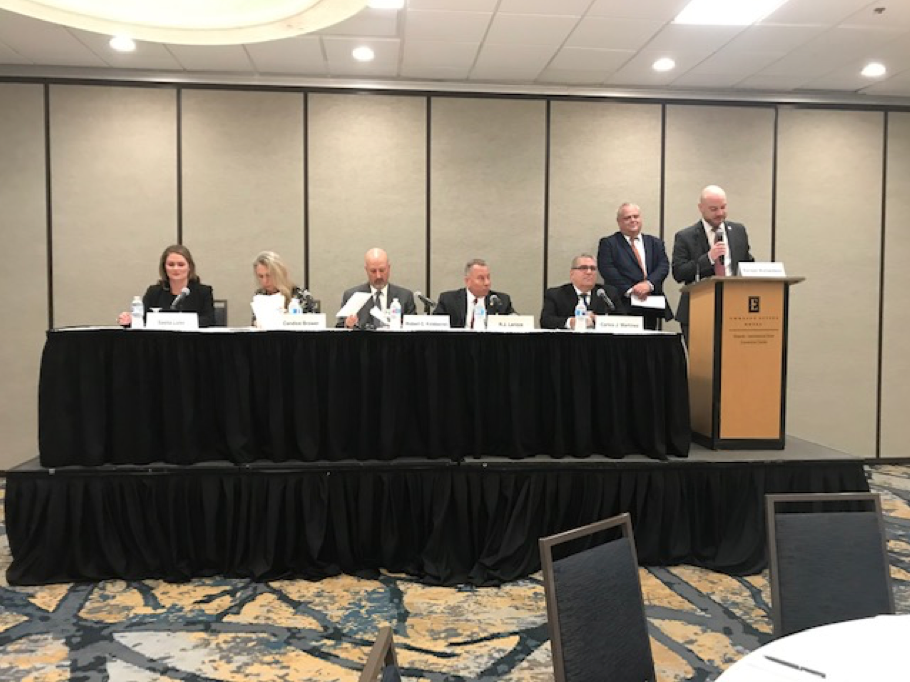 Government Lawyers Committee Update 6 Government Lawyers Committee, Business Professionals in a large meeting room, people behind a table on stage, symposium, seven people, five men, two women