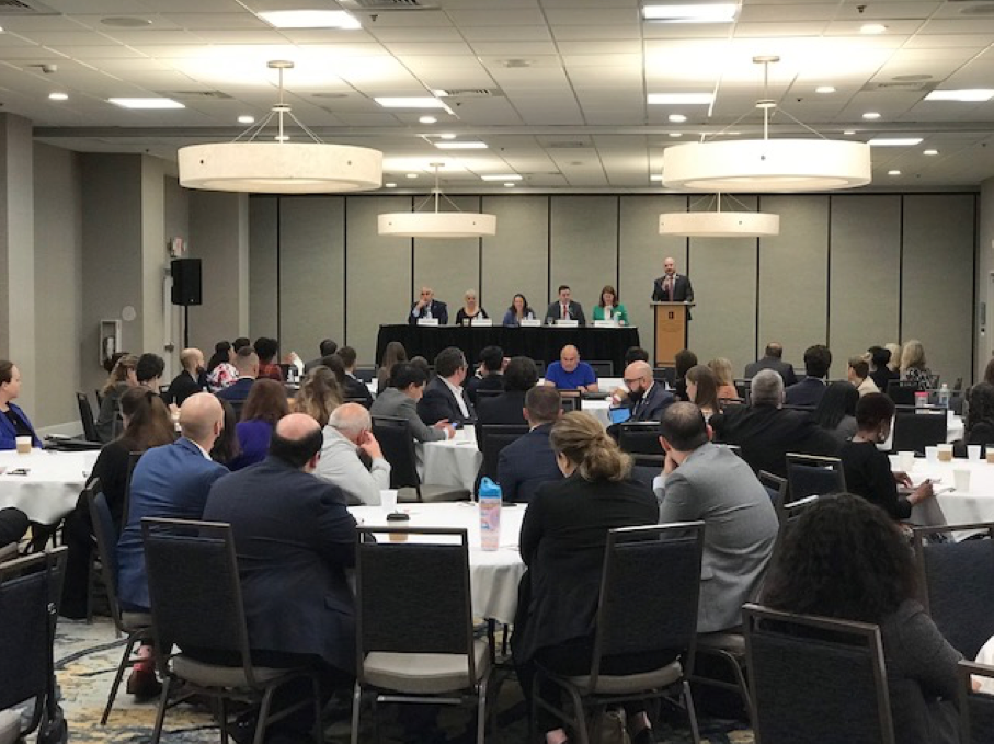 Government Lawyers Committee Update Government Lawyers Committee, Business Professionals in a large meeting room, man at a podium, people behind a table on stage Government Lawyers Committee, Business Professionals in a large meeting room, man at a podium, people behind a table on stage