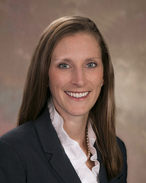Professional Caucasian woman, white shirt, black blazer, light brown hair, blue eyes